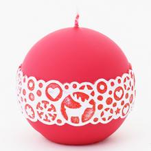 Vianočná sviečka v tvare gule, červená s bielym ornamentom.