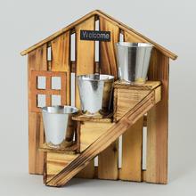 Drevený podstavec na kvetináče v tvare domu s nápisom 'Welcome'.