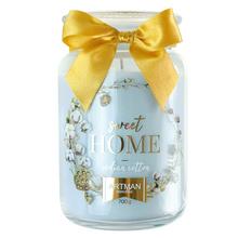 Sviečka v skle s modrým dizajnom a žltou stuhou.