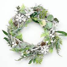 Vianočný veniec z prútia so zelenými a bielymi dekoráciami.