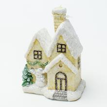 Keramický domček s vianočnou dekoráciou.