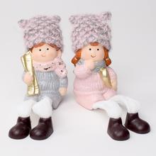 Dve keramické postavičky detí v zimných oblekoch s čiapkami.