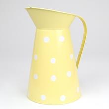 Žltý kovový džbán s veľkými bielymi bodkami.