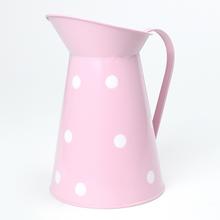 Ružový kovový džbán s veľkými bielymi bodkami.