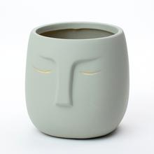 Sivý kvetináč s tvárou a otvorom.