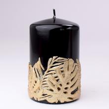 Čierna sviečka s dekoráciou listov monstera.