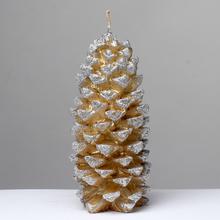 Zlatá vianočná sviečka v tvare šišky.