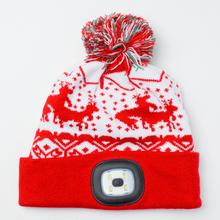 Červená čiapka s LED svetlom a vianočným motívom.