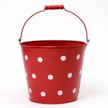Červené kovové vedro s bielymi bodkami.