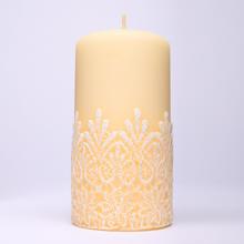 Sviatočná sviečka v krémovej farbe s ornamentálnym vzorom.
