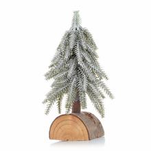 Zasnežený vianočný stromček na drevenom podstavci.