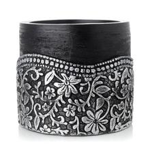 Čierny okrúhly svietnik s kvetinovým vzorom.