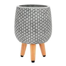 Šedý kvetináč s hexagonálnym vzorom a drevenými nohami.