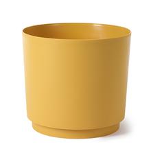 Okrúhly obal na kvetináče v horčicovej farbe.