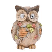 Hnedá socha sovy so solárnym osvetlením.