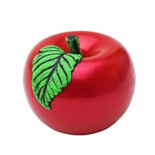 Červená sviečka vo forme jablka s zeleným lístkom.