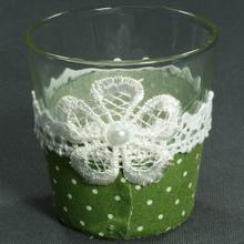 Pohár s krajkou a zeleným podkladom.