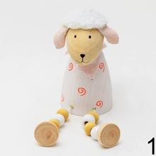 Drevená ovečka sediaca s farebnými guličkami.