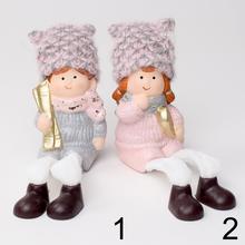 Dve keramické postavičky detí v zimných oblekoch s čiapkami.