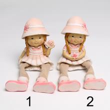 Dievčatko v klobúku sediace s ružovým oblečením.