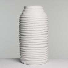 Biela keramická váza s vlnitým povrchom.
