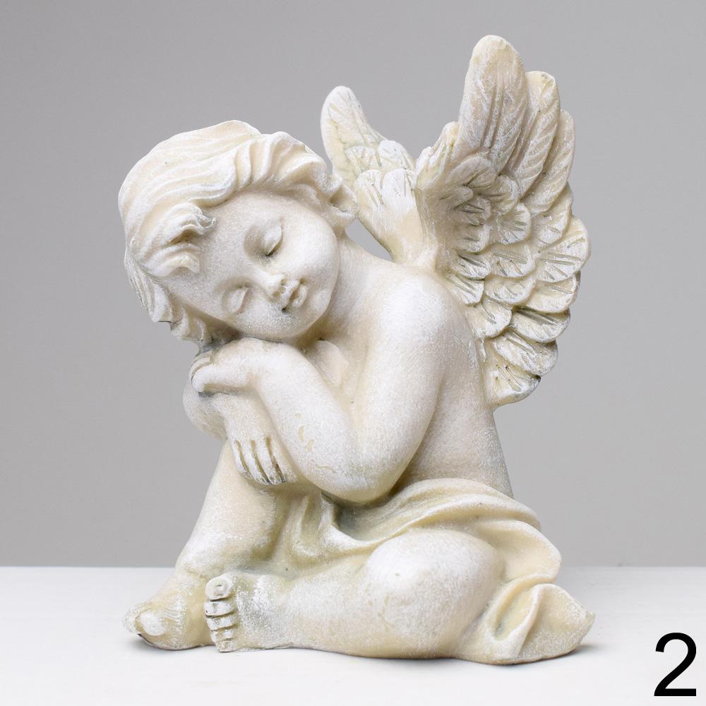 Sivý smútočný anjel s krídlami sediaci na zemi.