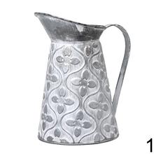 Malý kovový džbán so zeleným ornamentom.