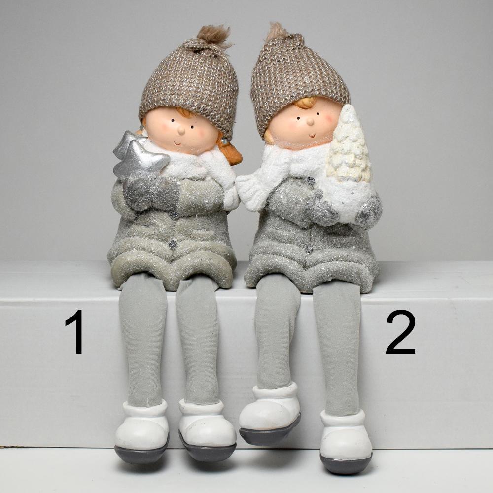 Dve deti s šedými nohami, oblečené v zimných čiapkach a šáloch, držia v rukách vianočné dekorácie.