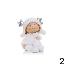 Dve deti sediace s čiapkami a parožím, biele keramické dekorácie.