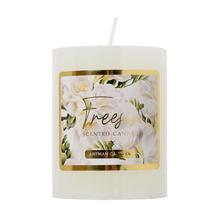 Biela vonná sviečka s kvetinovým dizajnom.