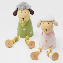 Drevená ovečka sediaca s farebnými guličkami.