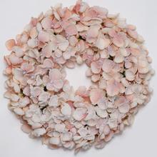 Ružovo-biely vianočný veniec s kvetinovými detailmi.