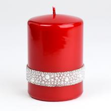 Červená sviečka s dekoratívnym pásikom.