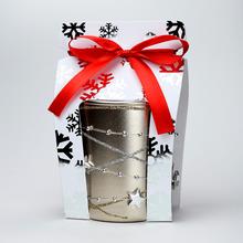 Vianočná sviečka v sklenenom obale s dekoráciou a červenou stuhou.