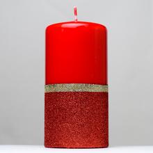 Červená vianočná sviečka s glitrami a zlatým pásikom.