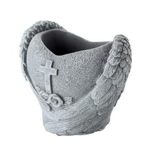 Obal v tvare srdca s krídlami a krížom, sivý cementový kvetináč.