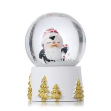 Snehová guľa s tučniakom v bielej, zlatej a červenej farbe.