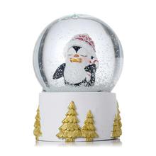 Snehová guľa s tučniakom v červenej čiapke.